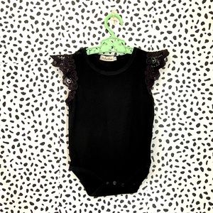 Black baby onesie with lace ruffle shoulder detail